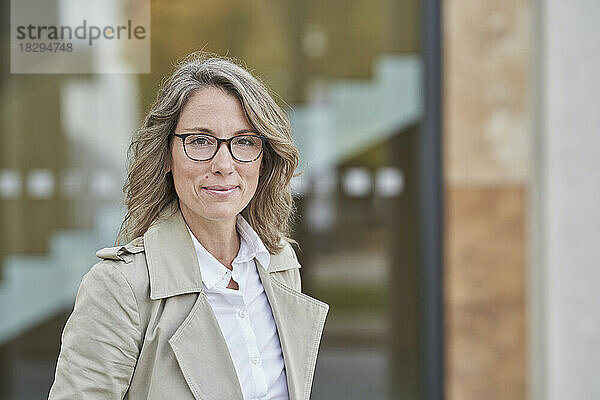 Selbstbewusste Geschäftsfrau mit Brille vor dem Gebäude