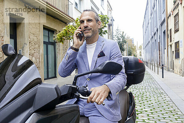 Reifer Geschäftsmann telefoniert auf dem Motorrad