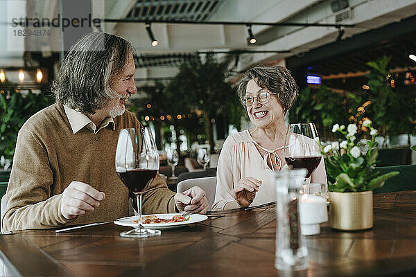 Ältere Männer und Frauen sitzen mit Weinglas am Tisch im Café