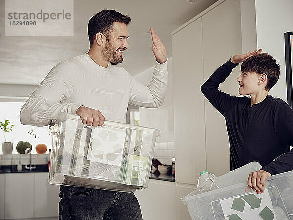 UK  London  Buckinghamshire  generations  sustainability  home  recycling  Dad and son having fun and high five after sorting the recycling.