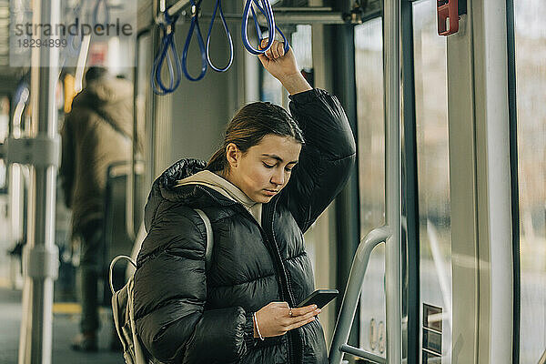 Teenager-Mädchen benutzt Smartphone in der Straßenbahn