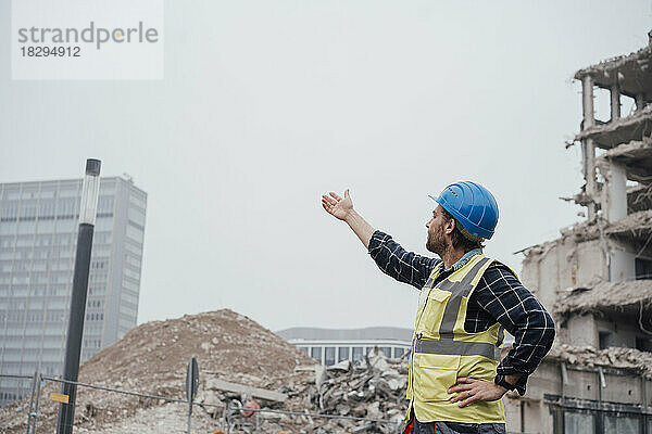 Arbeiter mit Schutzhelm gestikuliert auf der Baustelle