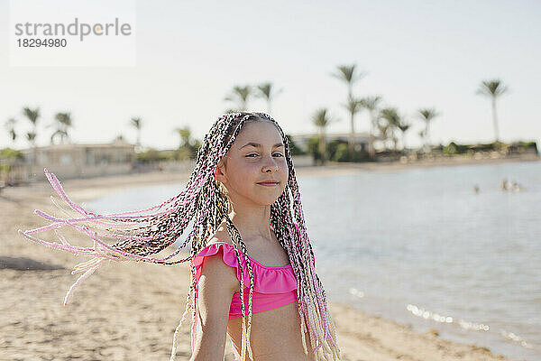 Mädchen mit geflochtenen Haaren steht am Strand