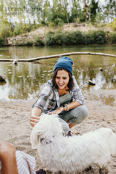 Glückliche junge Frau streichelt Hund im Park