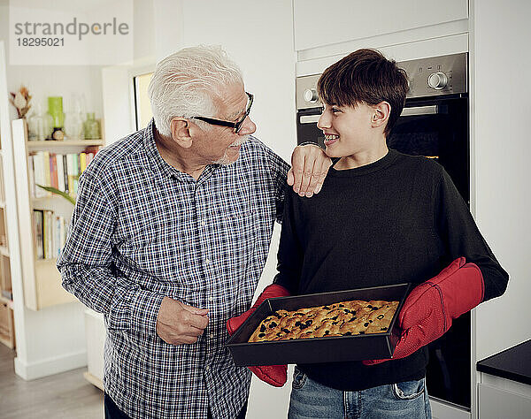 Großvater und Enkel halten Backblech mit frischem Focaccia-Brot in der Küche