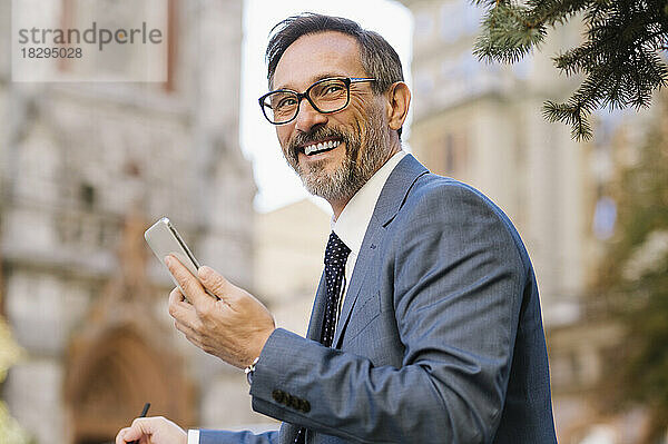 Glücklicher Geschäftsmann mit Brille und Smartphone