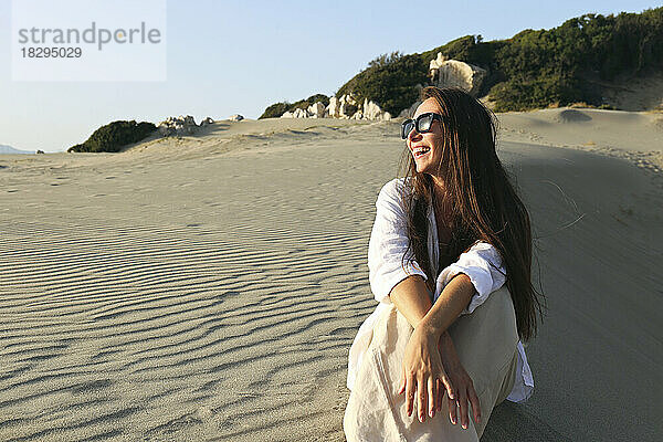 Glückliche junge Frau sitzt auf Sand am Strand  Patara  Türkei