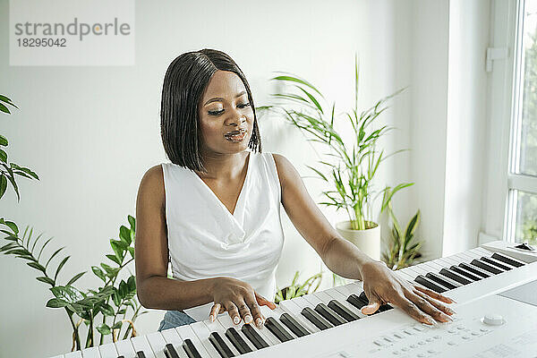Junge Frau spielt zu Hause Klavier