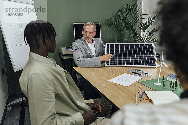 Reifer Geschäftsmann diskutiert mit Kollegen über Solarpanel