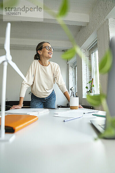 Lächelnde reife Geschäftsfrau  die am Tisch im Büro steht