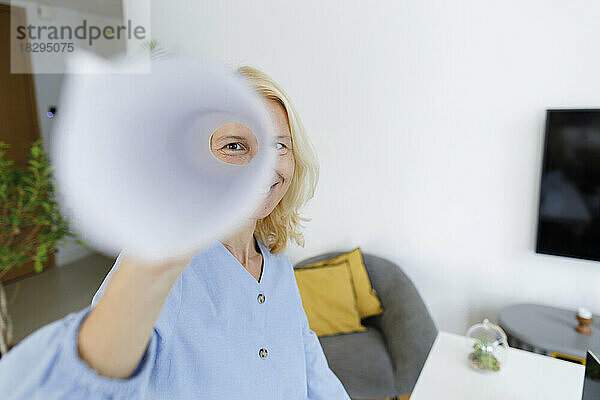 Woman looking through rolled paper at home