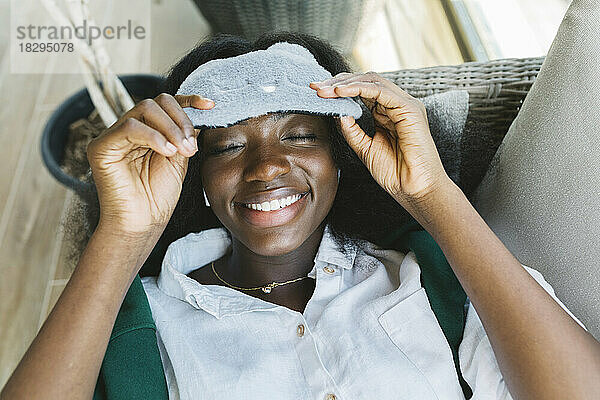 Happy woman with eye mask lying on sofa