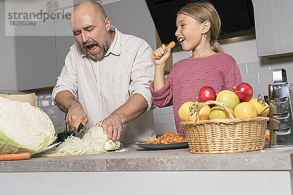 Father and daughter preparing healthy meal and having fun in kitchen at home