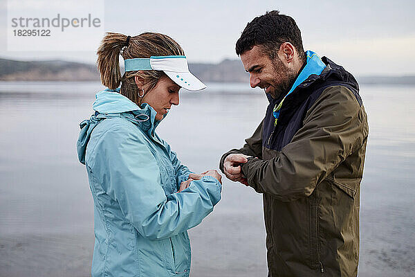 Paar stellt Smartwatch ein  bevor es am Strand läuft