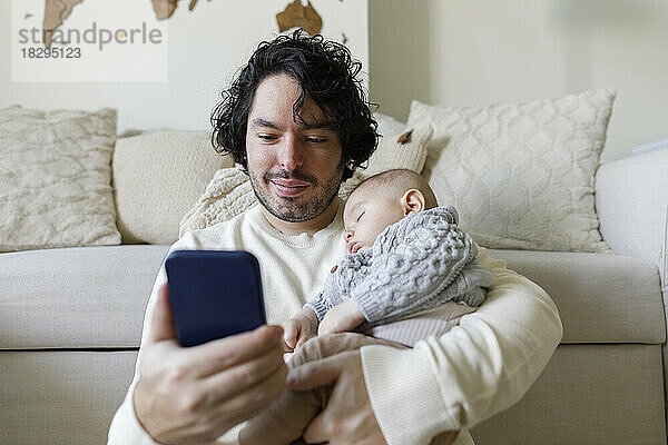 Vater benutzt Smartphone mit kleinem Jungen  der zu Hause schläft