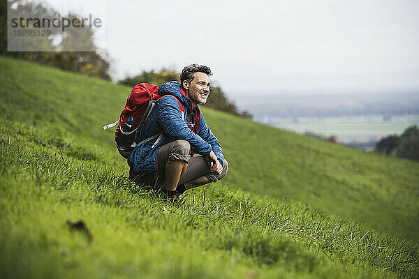 Lächelnder reifer Mann kauert auf Gras
