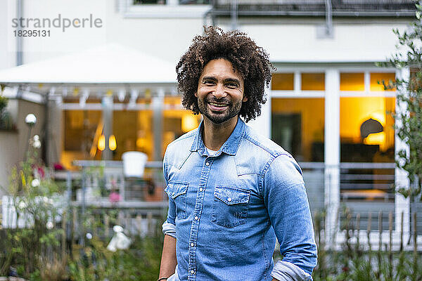 Glücklicher Mann mit Afro-Frisur  der vor dem Haus steht