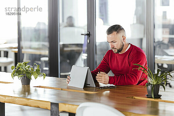 Geschäftsmann nutzt Tablet-PC am Schreibtisch im Coworking-Büro