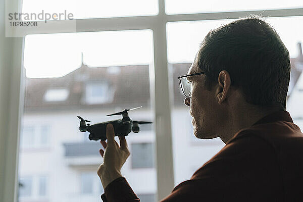 Geschäftsmann untersucht Drohne vor Fenster im Büro