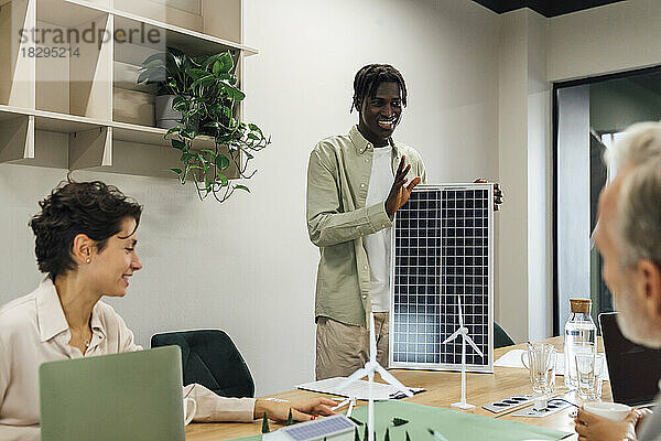 Junger Geschäftsmann diskutiert mit Kollegen im Büro über Solarpanel