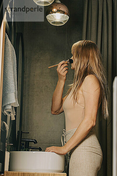 Blonde Frau schminkt sich im Badezimmer