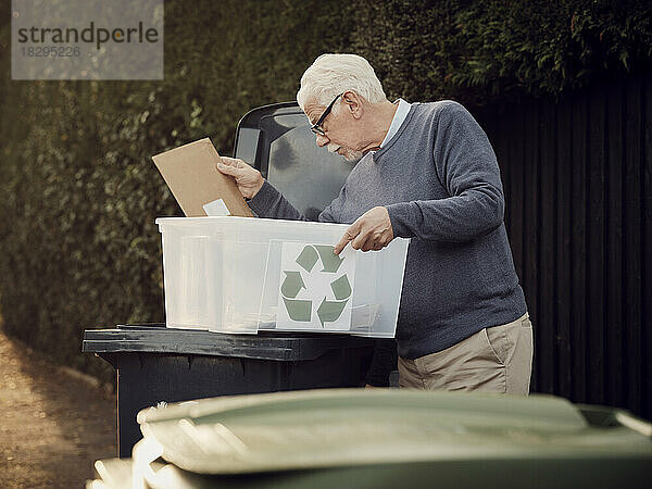 Älterer Mann wirft getrennten Recyclingabfall in den Mülleimer
