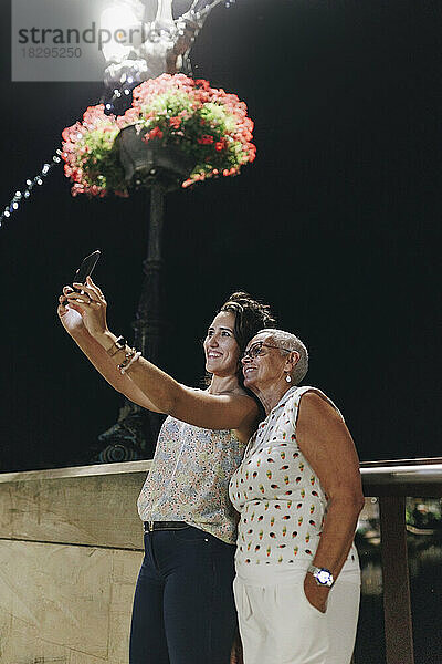 Junge Frau macht nachts ein Selfie mit einem Freund per Smartphone