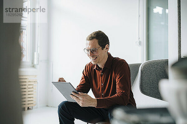 Happy businessman using tablet PC in office