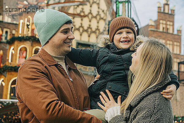 Glückliche Mutter und Vater genießen mit ihrem Sohn den Weihnachtsmarkt