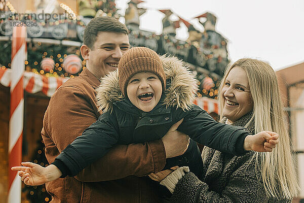 Glücklicher Vater und Mutter  die Spaß mit Sohn auf dem Weihnachtsmarkt haben