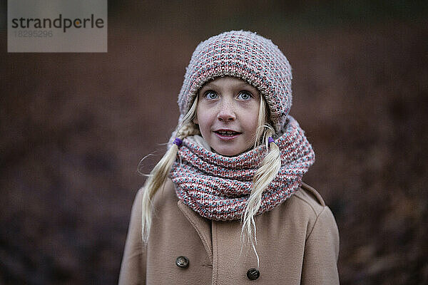 Lächelndes blondes Mädchen mit Strickmütze und Schal