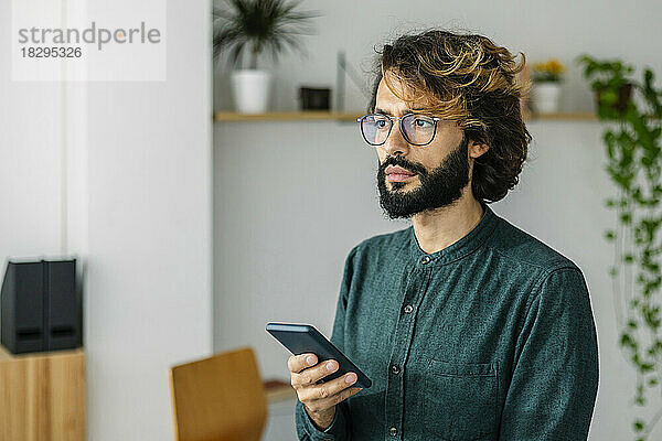 Freiberufler mit Brille und Smartphone im Büro