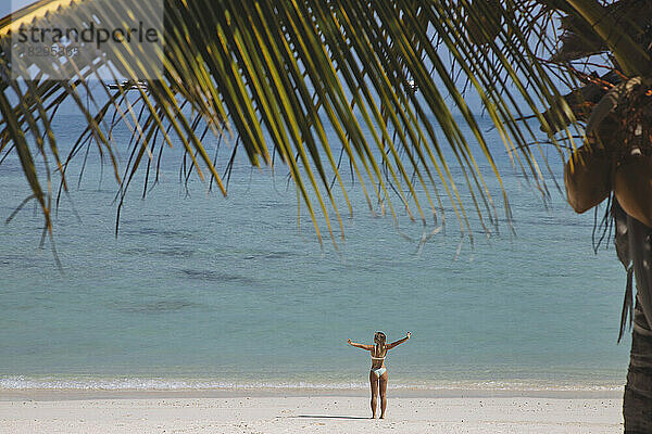 Carefree woman enjoying sunny day on shore at beach