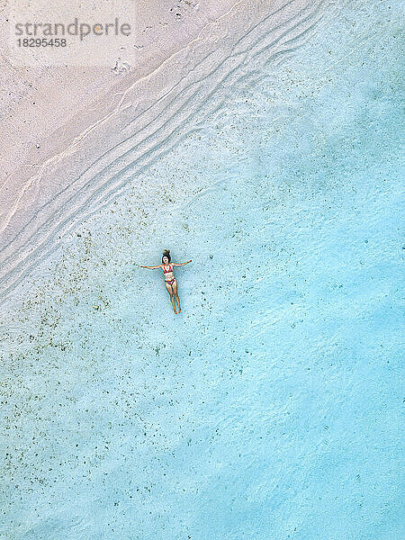 Frau schwimmt im blauen Meer am Strand