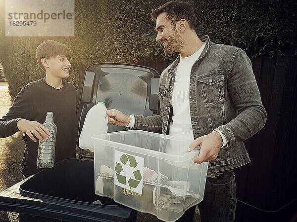 Father and son putting separated waste in waste bin