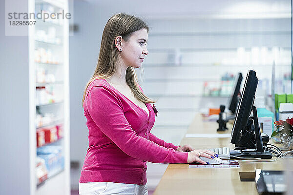 Apotheker arbeitet am Desktop-PC am Schalter in der Apotheke