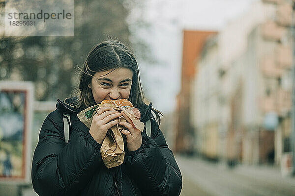Teenager-Mädchen isst Burger auf der Straße
