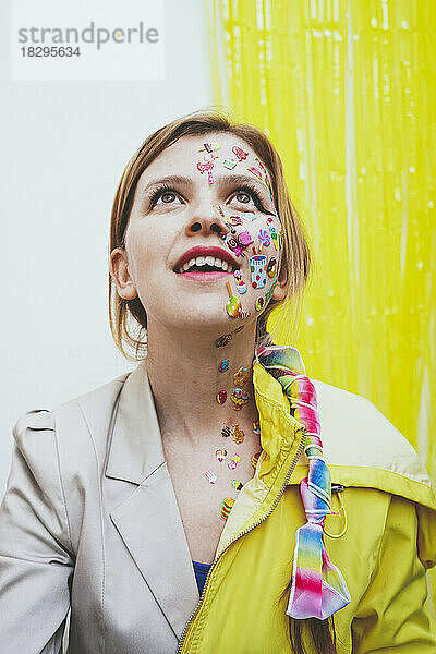 Glückliche Frau mit Aufklebern im Gesicht vor einer zweifarbigen Wand