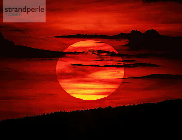 Sun setting against fiery red sky