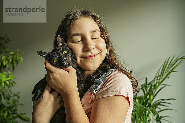 Lächelndes Mädchen streichelt zu Hause Katze