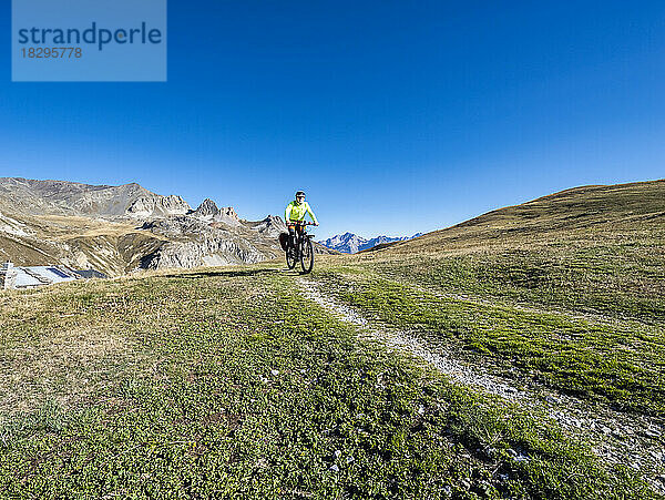 Älterer Mann fährt Mountainbike auf Trail unter blauem Himmel  Nationalpark Vanoise  Frankreich