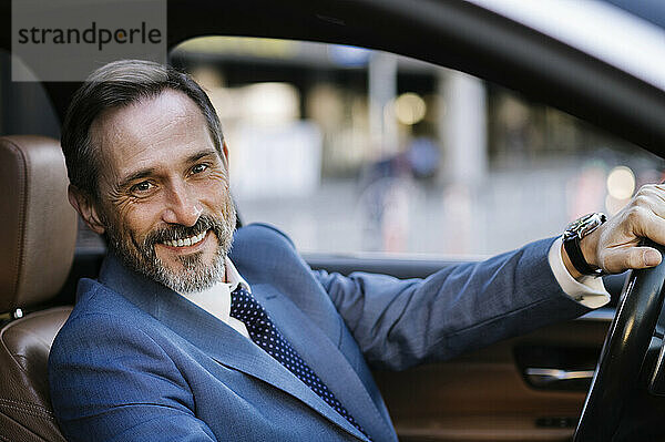 Happy mature businessman driving car