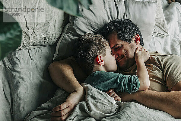 Lächelnder Mann mit schlafendem Jungen im Bett