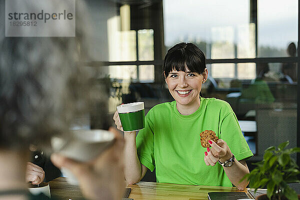 Happy woman wearing green t-shirt having a break in office