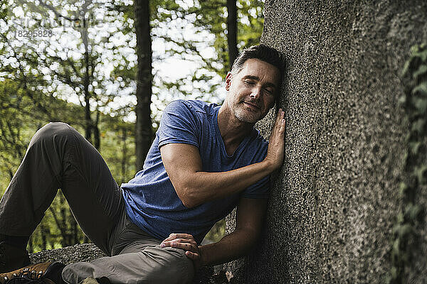 Reifer Mann entspannt sich auf einem Felsen im Wald