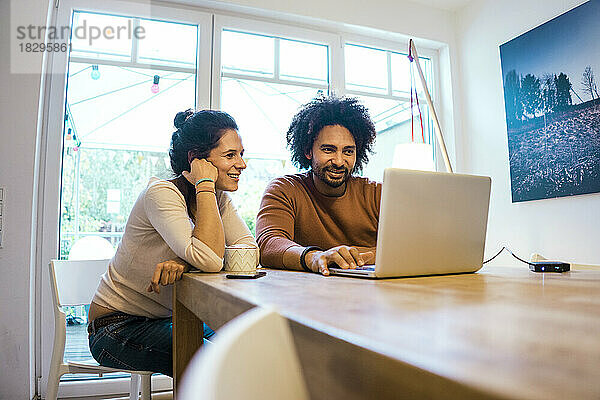 Happy man and woman using laptop at home