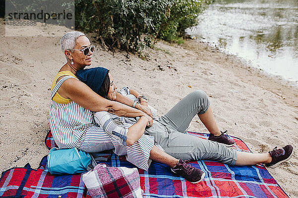 Freunde entspannen sich im Sand am Seeufer im Park