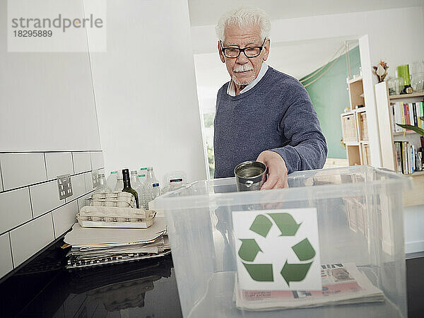 Älterer Mann legt getrennten Abfall in Recyclingbox