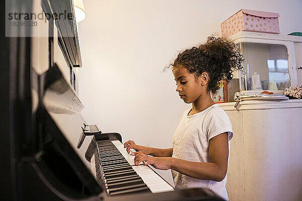 Mädchen übt zu Hause Klavier
