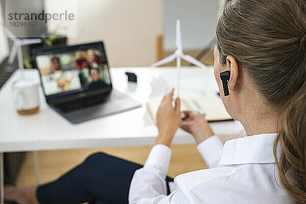 Geschäftsfrau mit In-Ear-Kopfhörern bei Videokonferenz im Büro